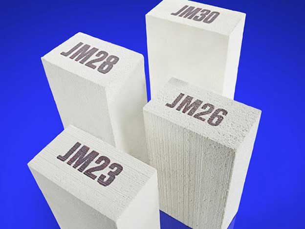 Four refractory casted bricks with different numbers on the surfaces, against a blue background.