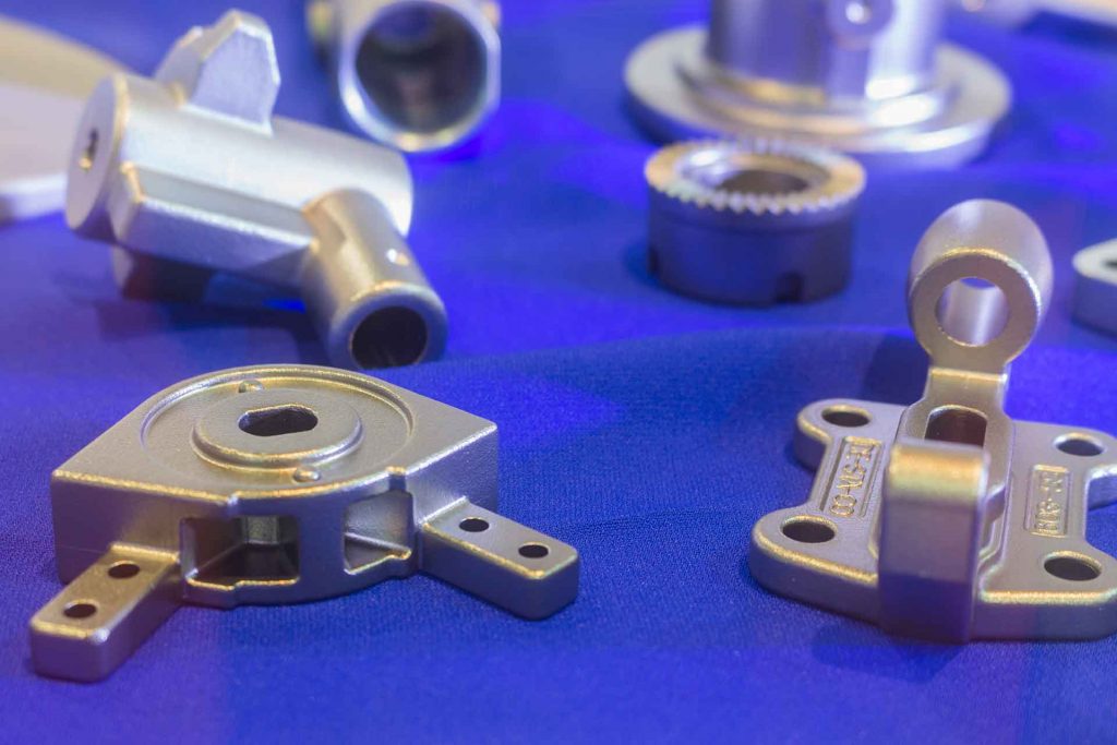 Casted metal parts arranged on a blue background.