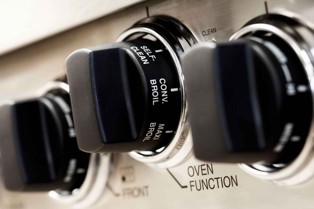 Three temperature knobs of an industrial stovetop.