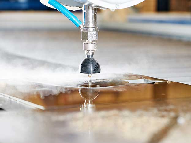 A close up image of a water jet cutting a large slab of refractory material.