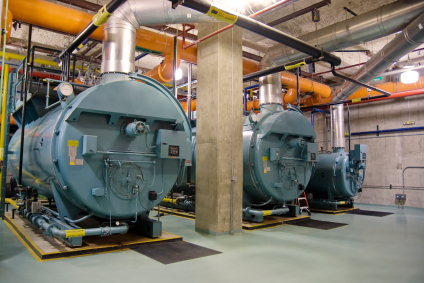 Three industrial high-heat boilers in a large boiler room.
