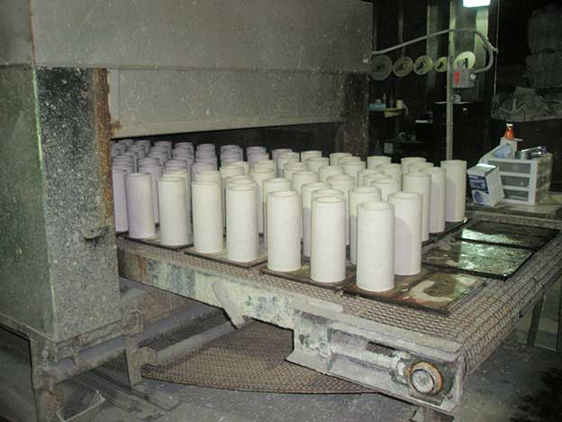 Vacuum-formed refractory castables lined up on a large industrial drying machine belt.